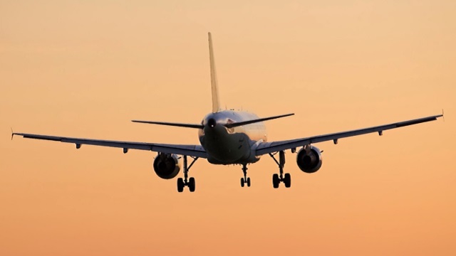 An aircraft taking off into an orange sky, about to raise its landing gear, powered by a complex electrical system design and wire harness integration.