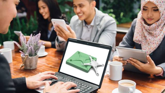 Konstrukteure, die an einem Tisch zusammenarbeiten und mit Hilfe eines CAD-Programms einen nachhaltigen Entwurf für die additive Fertigung erstellen