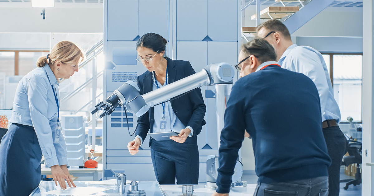 Manufacturing team of Industrial Robotics Engineers Gathered Around Table With Robot Arm