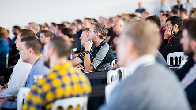Image of a group of men in an audience all looking toward the speaker.