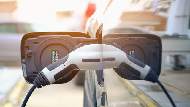 a person charging an electric vehicle using an EV charging station cord