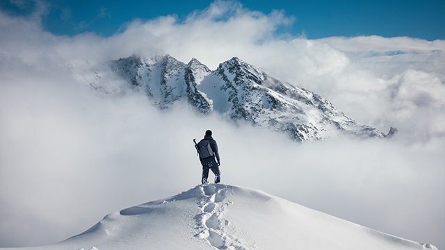 Man on top of mountain above the clouds