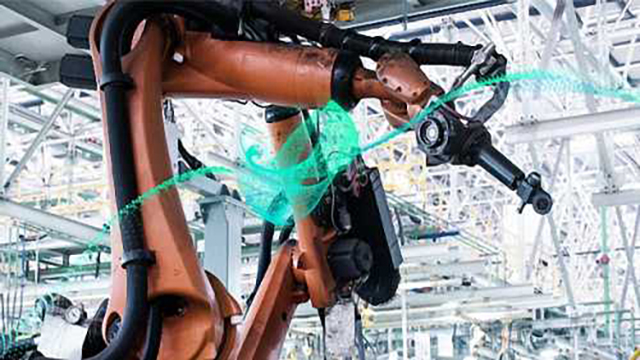 A robotic arm performs work in an industrial manufacturing facitlity.