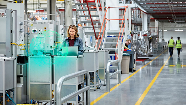 Woman working on computer on factory floor