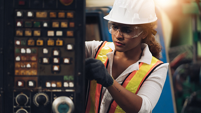 Female engineer with hardhat working on heavy equipment parts