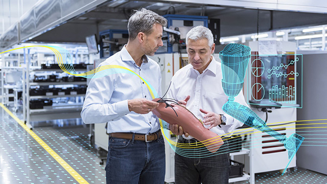Two men in a medical device manufacturing facility holding a prosthetic limb and analyzing data.