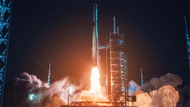 A rocket, taking off from the launch pad at night.
