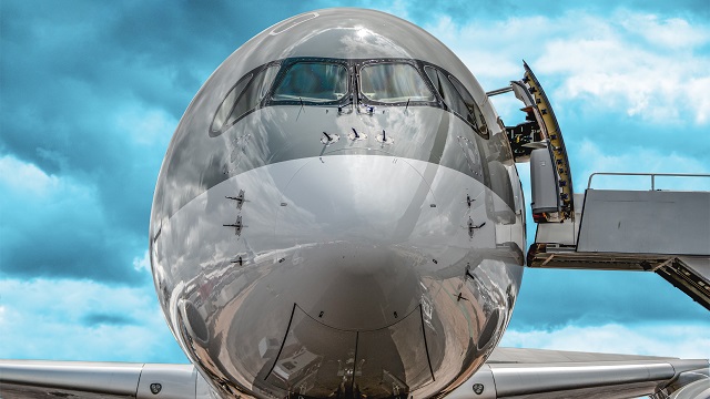 The front of a commercial aircraft including many items for which model-based systems engineering for aerospace improves development and maintenance such as the nose cone, cockpit windows and passenger door