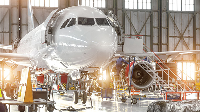 Two workers perform maintenance on a plane in a hangar – one of many aerospace processes impacted by supply chain management.