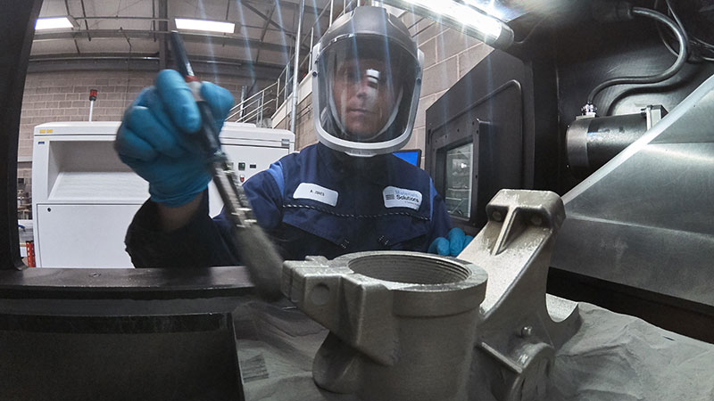 Additive manufacturing engineers discussing and pointing to preparation of metal 3D Printing parts for manufacturing